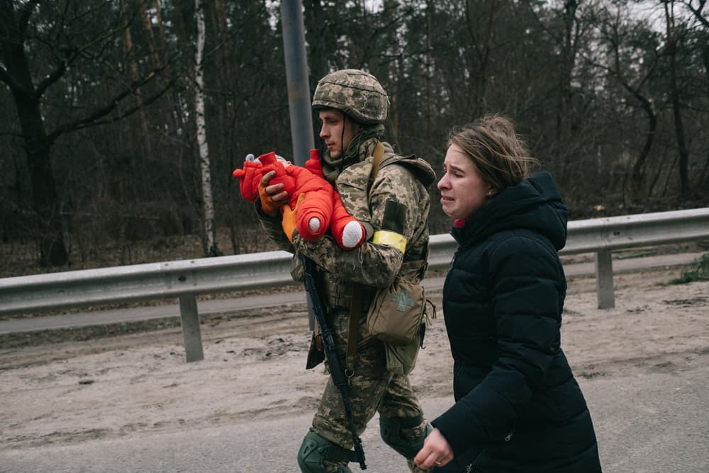 Український солдат допомагає Юлії Павлюк та її доньці Еммі евакуюватися з передмістя Києва Ірпеня, яке російські війська намагалися захопити в рамках їхньої спроби оточити столицю 5 березня